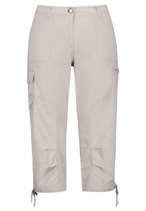 Beżowe spodnie cargo wykonane z lekkiego materiału, posiadające wiele kieszeni, zszyte wzory oraz regulowane sznurki przy mankietach.