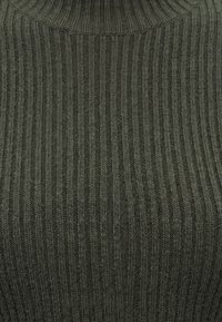 Tissu tricoté vert foncé avec une texture côtelée verticale et un col montant montrant des détails en gros plan.
