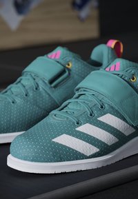 Tyrkysové športové topánky s štruktúrovaným zvrškom, bielym logom s tromi pruhmi, polstrovaným členkom a kontrastnými ružovými akcentmi.