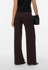 Vida byxor i mörkbrun, slät tyg med hög midja, minimalistisk design och en bakficka.