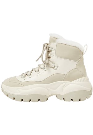 Beige og off-white vinterstøvle med tyk ru ydersål, snørelukning foran og blødt pelsfor ved ankellukningen.