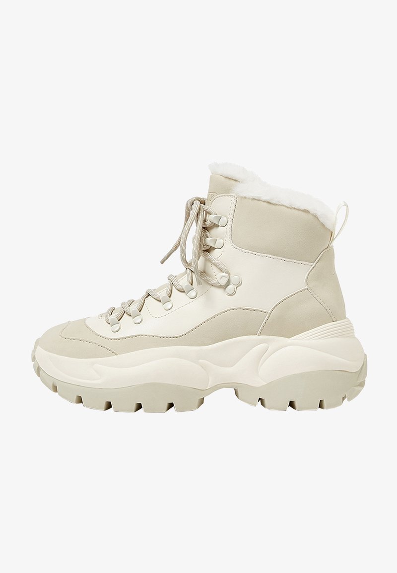 Botte d’hiver beige et blanc cassé avec une semelle épaisse et robuste, fermeture à lacets à l’avant et doublure douce en fourrure au niveau du col de la cheville.