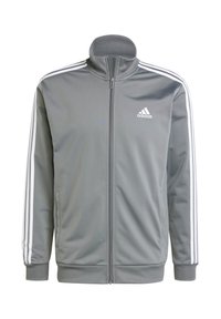 Sivá zipsová bunda vyrobená z hladkej tkaniny, so bielymi pruhmi pozdĺž ramien a rukávov, a vyšitým logom na hrudi.