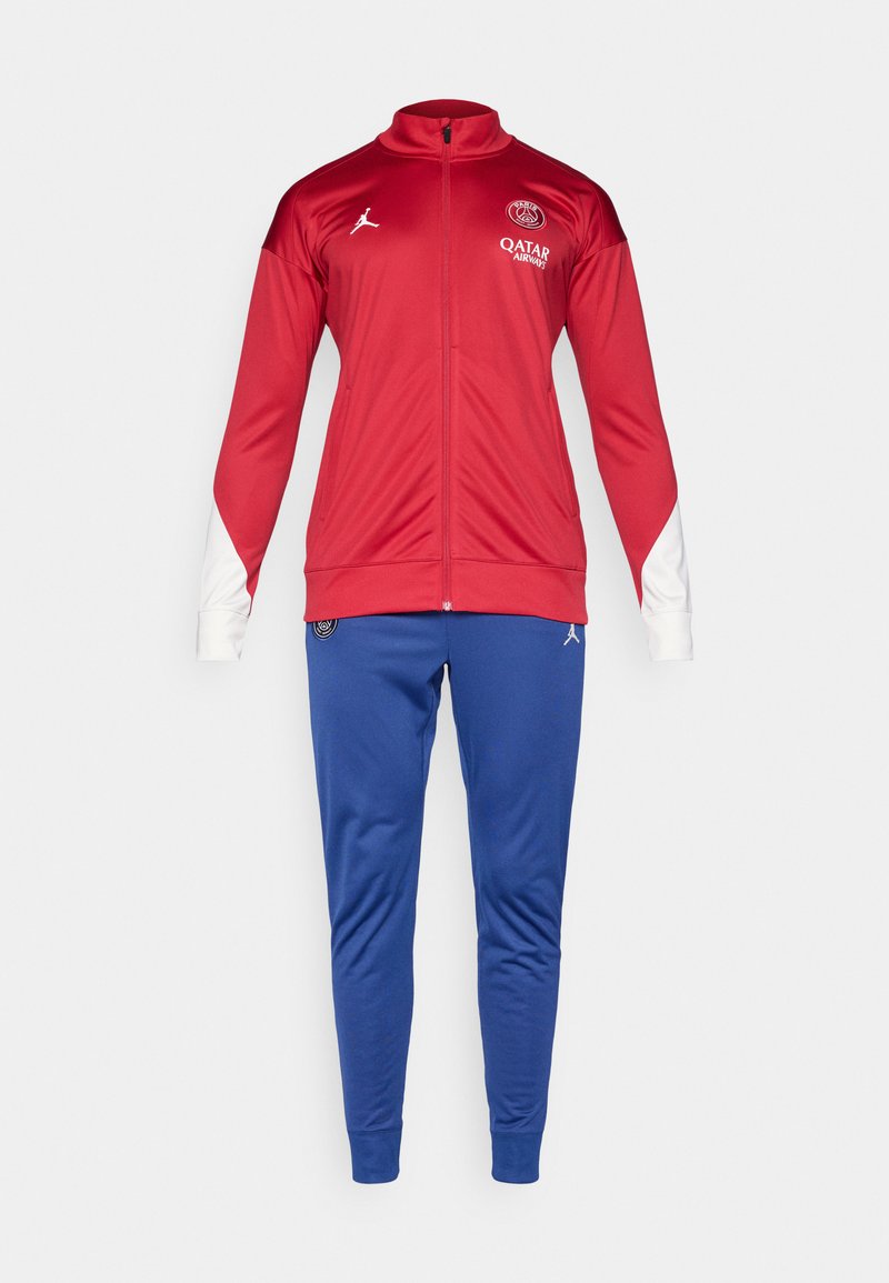 Chaqueta de cierre rojo y blanco con logo, combinada con pantalones ajustados azules que también presentan un logo. Ambos están fabricados con un material suave y elástico.