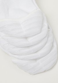White sock featuring textured grip patterns on the sole, smooth fabric, and reinforced toe and heel areas for durability.
