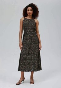 Vestido midi preto com pequeno padrão floral bege, cintura ajustada e alças ajustáveis. Usado com sapatos de salto preto. Tecido com textura suave.
