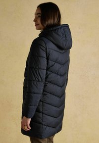 Granatowa kurtka puchowa z kapturem, z haftowanym wzorem i pionowymi szwami. Materiał ma gładką teksturę i średnią długość.