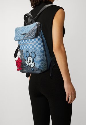 Sac à dos en denim bleu avec un rabat pliant, des motifs en damier et floraux, mettant en vedette un Mickey Mouse en dessin animé, et un détail de porte-clés rouge en dessin animé.
