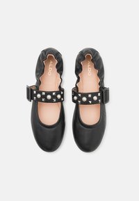 Black leather ballet flats with a ruffled edge and a strap adorned with metal studs and pearl accents. Lined with pale pink material.