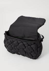 Borsa a spalla nera intrecciata con un aspetto morbido e imbottito. Chiusura a scatto magnetico e logo DKNY sulla tracolla. Tasca interna con zip.
