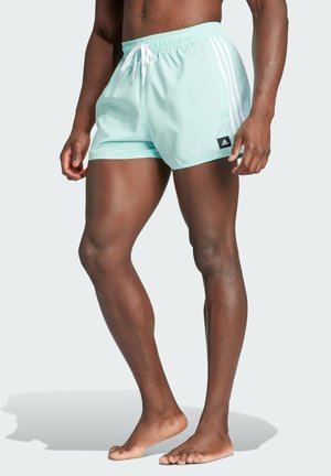 Pantaloni da bagno verde menta con strisce laterali bianche, vita elastica e coulisse. Presenta una piccola etichetta logo nera sulla gamba.