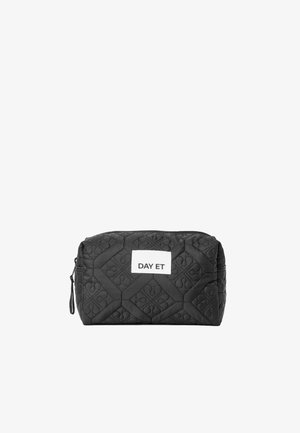 Sac de maquillage noir matelassé de forme rectangulaire, avec une étiquette blanche bien en vue portant l'inscription "DAY ET". Un motif texturé ajoute du détail.
