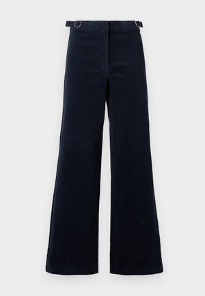Pantalones de pana anchos en un azul marino oscuro con correas ajustables con hebilla en los laterales de la cintura, sobre un fondo liso.