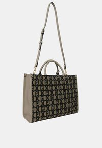 Borsa tote nera e beige con un motivo a logo ripetuto, rifiniture in pelle sintetica liscia, doppi manici superiori e una tracolla removibile.