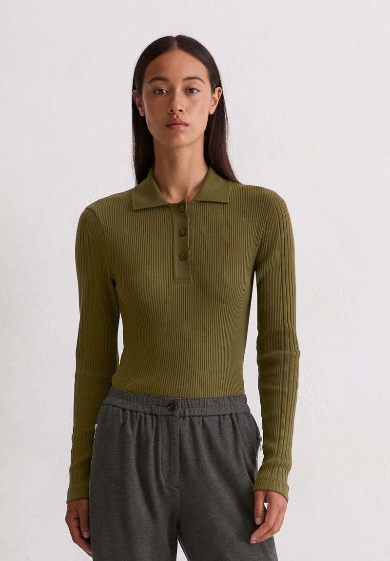 Olijfgroen geribd longsleeve polo shirt met een kraag en drie knopen, gecombineerd met grijze broek met elastische tailleband en een zijzak.