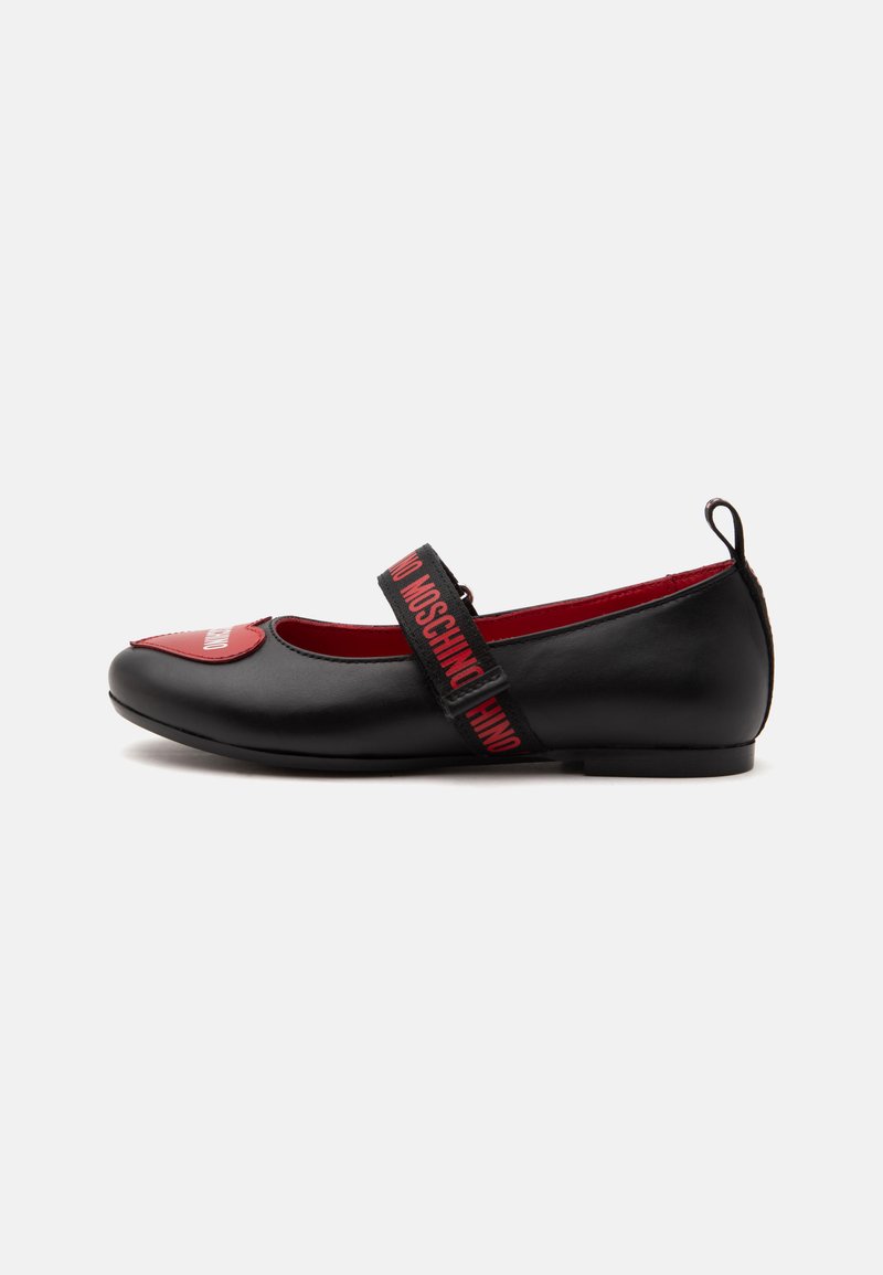 Chaussure plate Mary Jane noire avec intérieur rouge, patch rouge sur la pointe et bride noire avec texte du logo Moschino rouge.