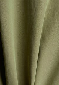 Tessuto strutturato in verde oliva tenue, con morbide pieghe e un aspetto leggermente intrecciato; materiale leggero e liscio.