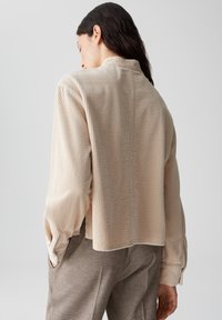 Beige corduroy shirt met een ontspannen pasvorm, met lange mouwen en een achternaaddetail. Getextureerde stof met ribbelpatroon.