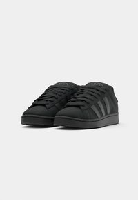 Svarta sneakers med en texturerad ovandel, med tre tonala ränder och rund tå. Snörningsdesign med platt sula och logotyp på tungan.