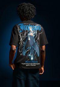 Černé grafické tričko s modrobílou anime postavou obklopenou blesky. Obsahuje text "Jinwoo" a citát "Shadow Monarch."