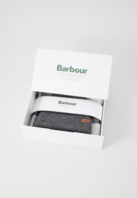 Caixa de presente Barbour contendo um cachecol de malha cinza e um cobertor estampado. A caixa possui um exterior branco com detalhes em verde e marrom do logótipo.