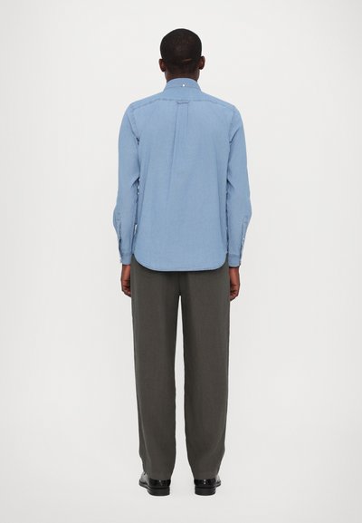 Light blue long-sleeve shirt with button-down collar, straight hem, and tailored fit, paired with gray wide-leg trousers and black shoes.