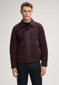Giacca da uomo in suede bordeaux con zip frontale, colletto a punta e due tasche sul petto. Presenta una finitura testurizzata ed è progettata per una vestibilità slim.