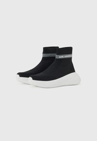 Black knit ankle sneakers with a ribbed cuff, contrasting white sole, and logo accent. Features a textured upper for breathability.