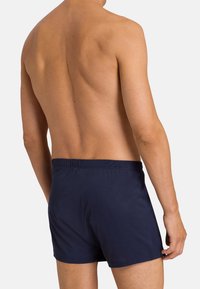 Námořnické modré plavkové šortky s elastickým pasem, vyrobené z hladkého, lehkého materiálu, s přiléhavým střihem a minimem švů.