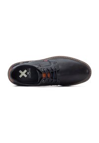 Zapato de cuero negro con puntera redonda, diseño de cordones, acentos marrones y costuras alrededor de la suela. Interior plano y texturizado.