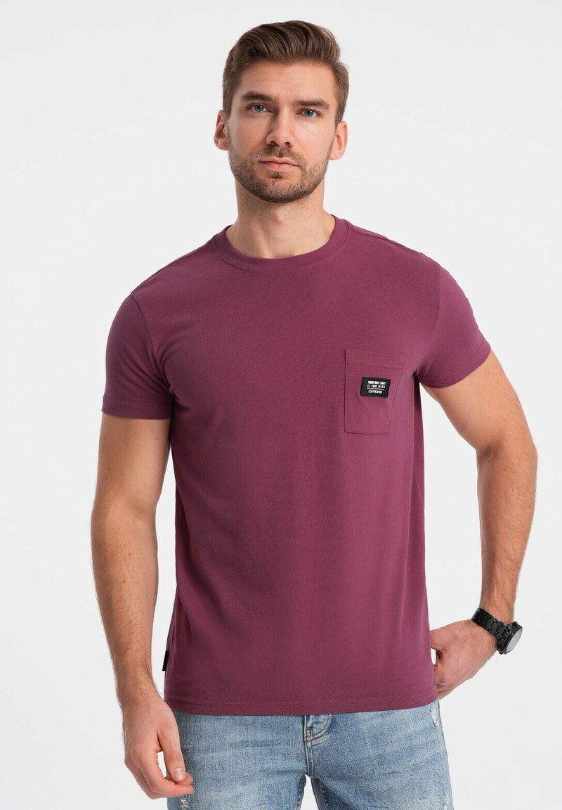 Korte ærmer, rundhals T-shirt i en dyb maroon farve, med en venstre brystlomme med et karakteristisk sort mærke. Blød stoftekstur.