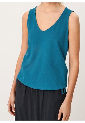 Blågrønt ærmeløst top med V-hals, ribbet tekstur og snoredetaljer ved hæmningen. Kombineret med en mørk, flydende nederdel.