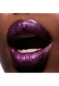 Glatte læber dækket af en metallisk lilla nuance, der har en glitrende tekstur og en glat finish, som afslører hvide tænder og en åben mund.