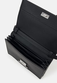 Borsa a mano nera strutturata in materiale sintetico testurizzato. Caratterizzata da una chiusura con gancio in metallo e da diversi scomparti per carte all'interno. Interno liscio.