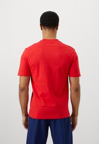 Κόκκινο κοντό μανίκι μπλουζάκι από βαμβάκι, με στρογγυλή λαιμόκοψη και λεία υφή, με ελάχιστο σχέδιο και χωρίς ορατά μοτίβα.