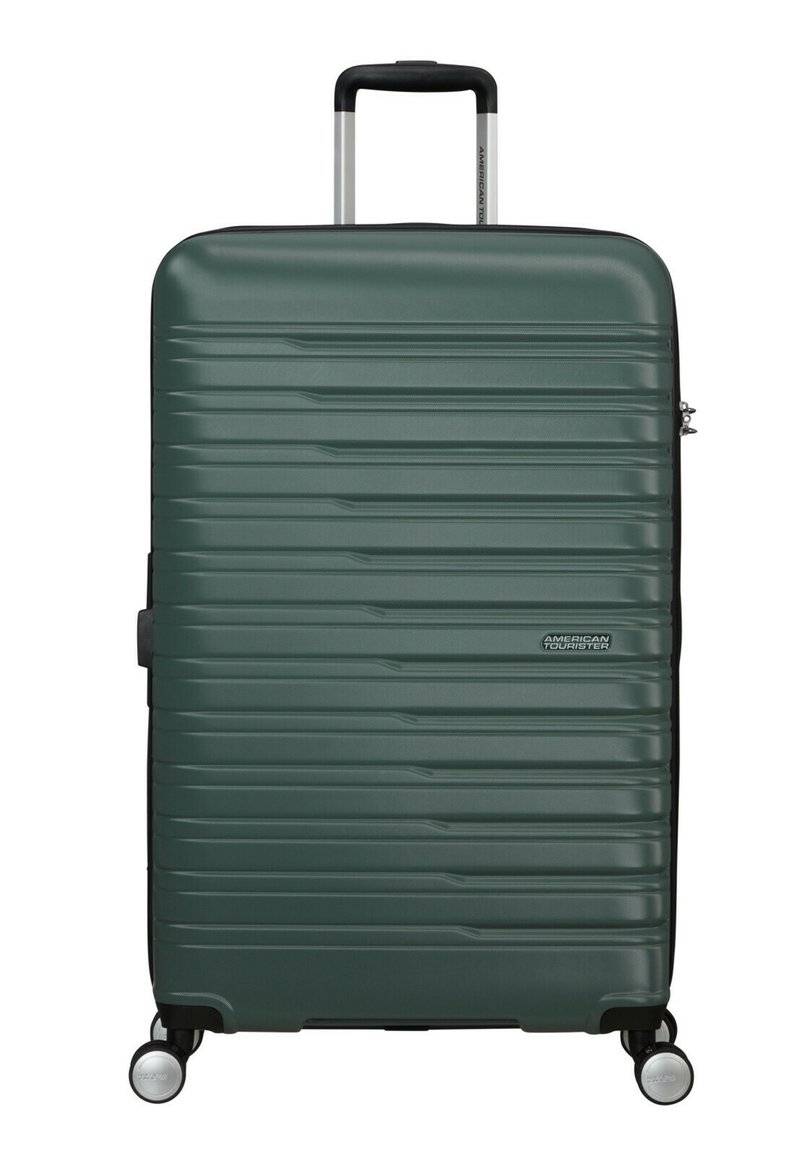 Maleta rígida en verde oscuro, con un diseño estriado texturizado, mango telescópico y cuatro ruedas giratorias negras.