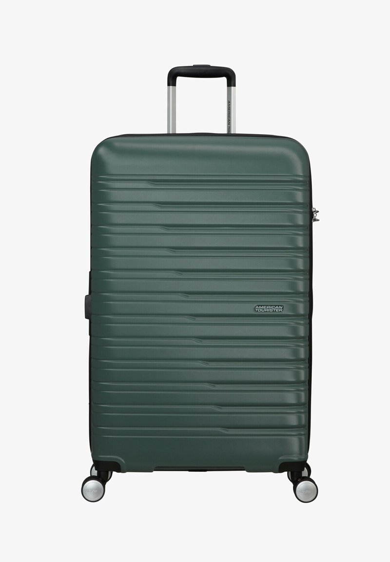 Maleta rígida en verde oscuro, con un diseño estriado texturizado, mango telescópico y cuatro ruedas giratorias negras.