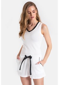 Biały top bez rękawów z teksturowanym wzorem i czarną lamówką w kształcie litery V, połączony z dopasowanymi białymi szortami z troczkiem i kieszeniami bocznymi.