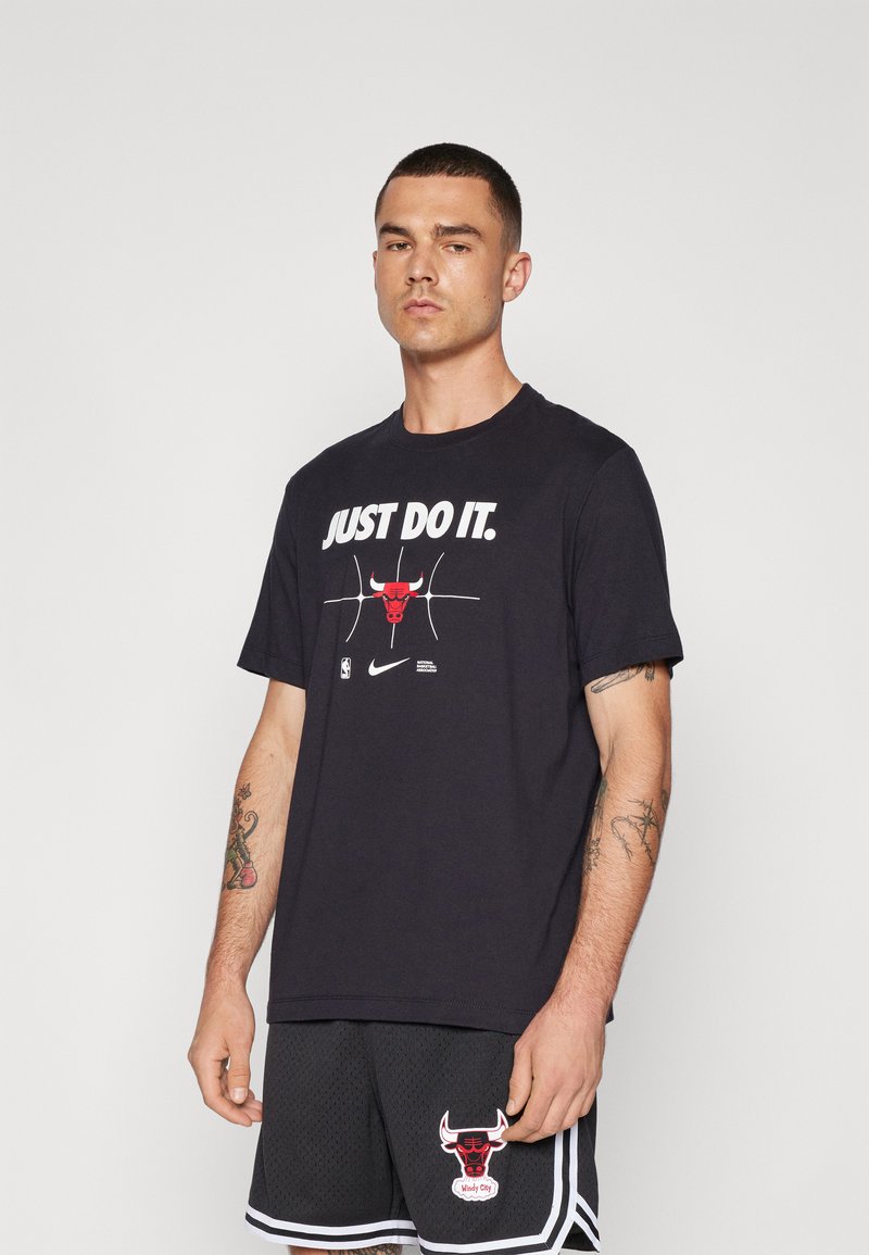 Melna kokvilnas T-krekls ar "JUST DO IT" tekstu, sarkanu bullīša grafiku un apaļu kakla izgriezumu. Kombinēts ar melniem šortiem ar bullīša logo.