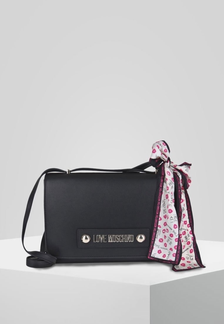 Borsa a tracolla nera in ecopelle con placca logo argentata, caratterizzata da una sciarpa a motivi rosa e bianca annodata al manico. Design piatto.