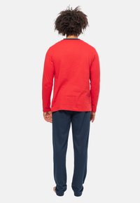 Rode langarmtop van textuurstof, gecombineerd met marineblauwe broek. Eenvoudige, relaxte fit, zonder zichtbare patronen of hardwaredetails.