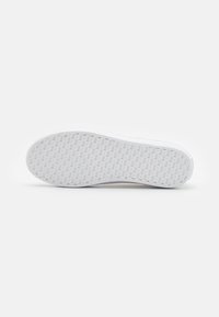 White sneaker sole with a textured rubber surface, featuring a diamond pattern for grip and support, smooth edges, and minimalistic design.