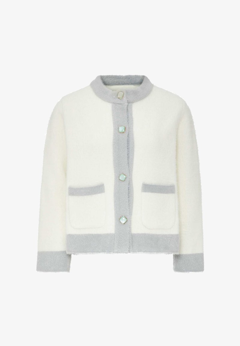 Witte pluizige cardigan met grijze accenten, voorzien van een hoge kraag, vier knopen aan de voorkant en twee opgestikte zakken aan de voorkant.