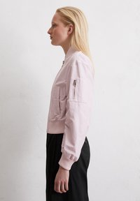 Helle rosa Bomberjacke aus glänzendem Material, mit gerippten Bündchen und Saum, seitlicher Tasche mit Reißverschluss und strukturierter Silhouette.