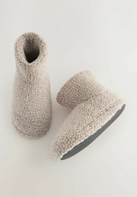 Beige Fleece-Ankle Boots mit weicher Textur und Gummisohle; geschwungene Form mit hohem Schaft, die Wärme und Komfort bietet.