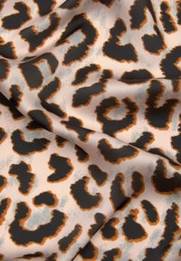 Tkanina z leopardjim vzorom z mehko teksturo, ki prikazuje črne madeže obrobe v oranžni barvi na bledi roza podlagi s subtilnimi sivo odtenki.