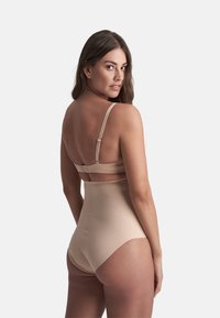 Controladora de talle alto beige con tirantes ajustables, textura suave y cierre de gancho en la parte posterior. Proporciona cobertura completa.