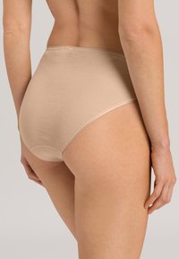 Slip in cotone beige con design senza cuciture, vita bassa e texture liscia. Il tessuto sembra morbido e flessibile.