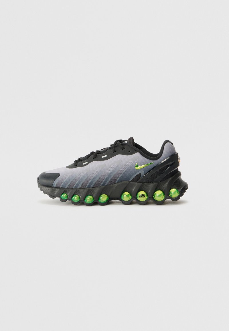 Zapatillas Nike con parte superior en degradado gris, acentos en negro y distintivas cápsulas de amortiguación verdes en la suela. Materiales de tela y goma.