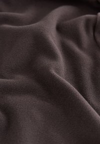 Soft, dark brown fabric with gentle folds and a slightly fuzzy texture filling the frame.